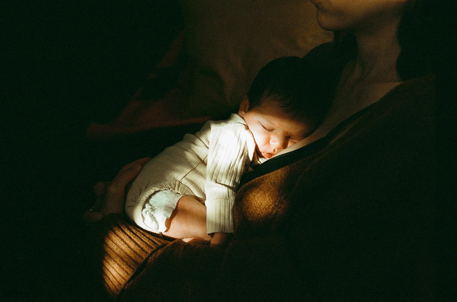 Mom holding her baby on her chest during a night feed